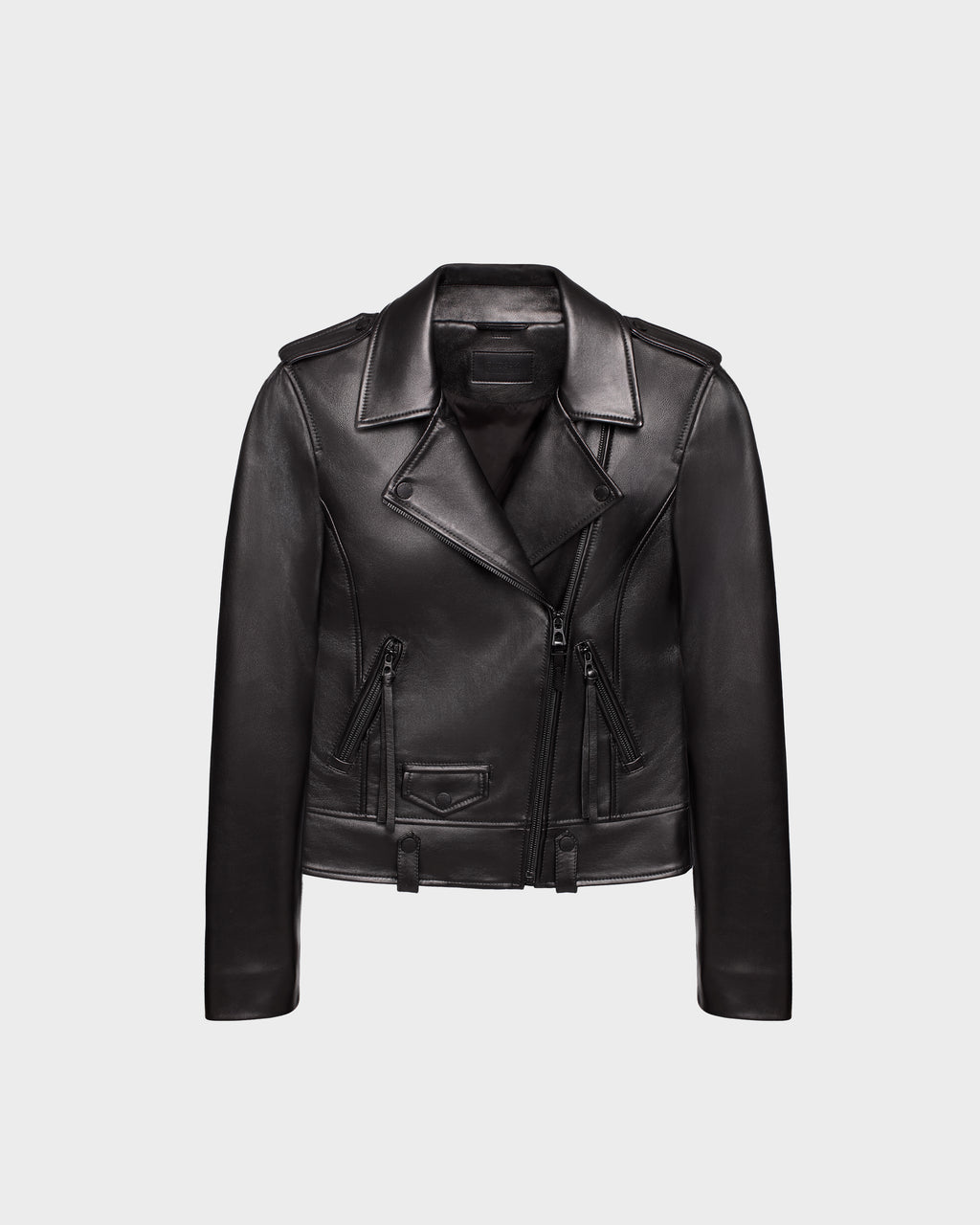 The Rudsak MERGO - 8122009 BLACK is a womens lambskin biker jacket featuring an asymmetrical front zipper, wide lapels, zippered side pockets, and a waist belt, shown against a plain light gray background.