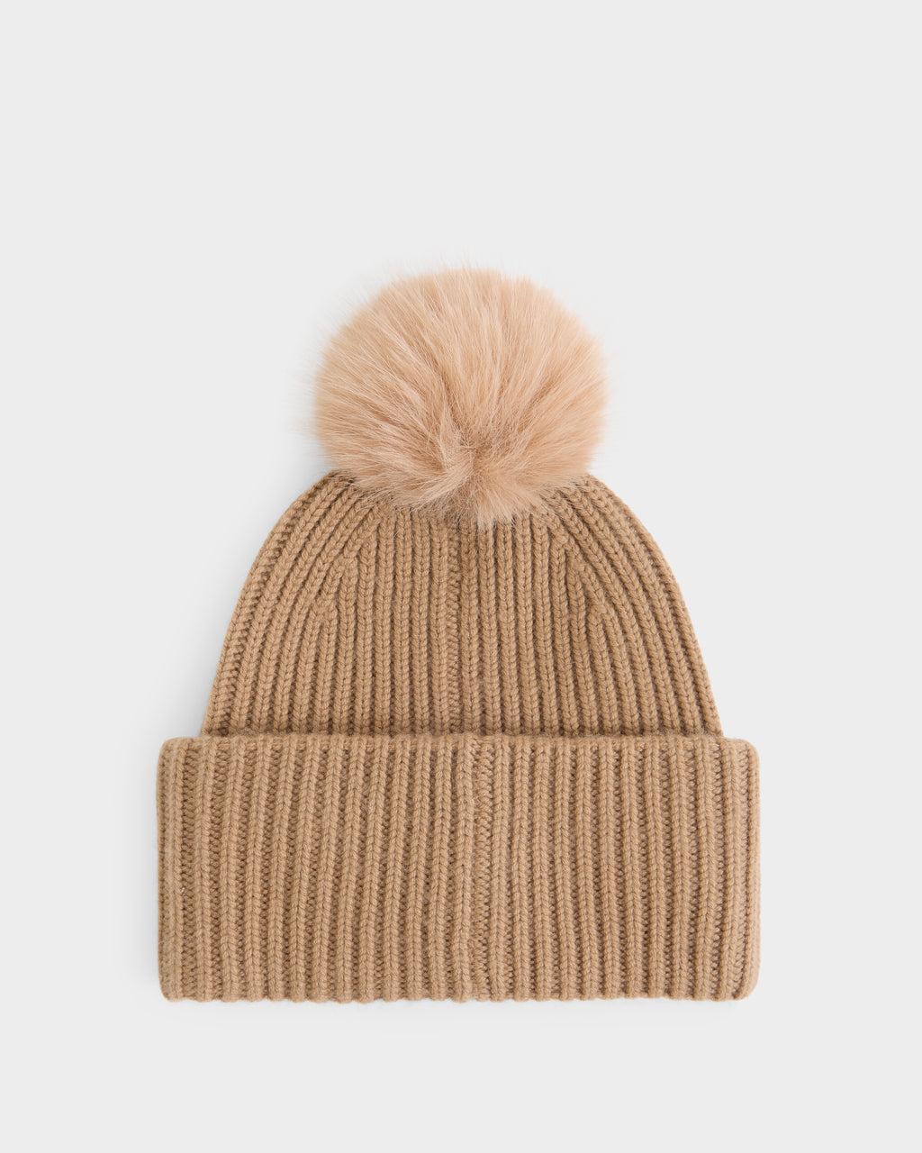 A true cold-weather essential, the DARA - 8425019 Camel by Rudsak is a tan knit women’s cashmere tuque featuring a wide folded brim and a fluffy faux fur pom pom on top, displayed against a plain white background.