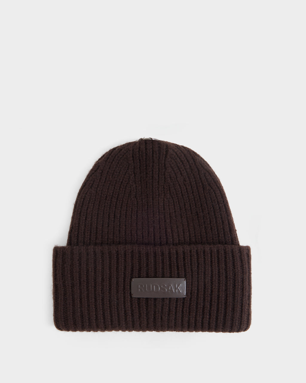 Here’s a revised version of your sentence using the provided product data: The DARA - 8425019 Espresso is a women’s winter hat by Rudsak, featuring a ribbed knit construction in espresso with a folded brim and a rectangular Rudsak logo patch on the front, displayed on a white background.