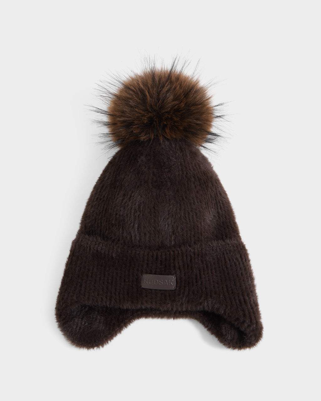 The Rudsak ICE - 8426519 Espresso is a dark brown, ribbed winter hat with ear flaps and a large, fluffy brown pom-pom on top, displayed against a white background.