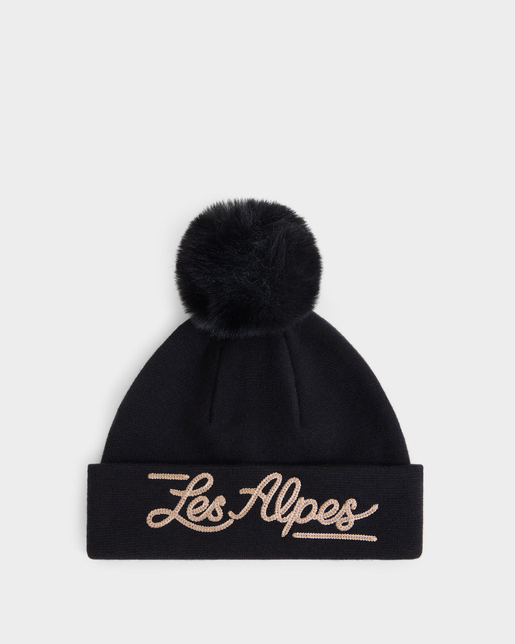 The Rudsak ESTELLA - 8426521 Black is a black knit beanie featuring a large pom-pom on top and “Les Alpes” embroidered in cursive beige letters on the folded brim, displayed against a plain white background.
