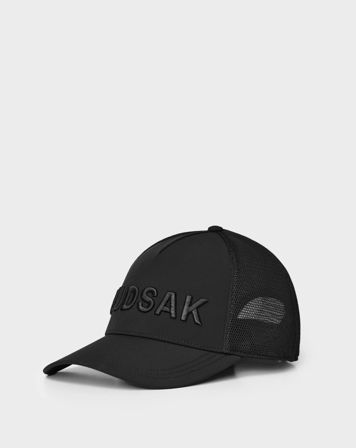 The Rudsak ALFIE - 9424004 Black is a unisex baseball cap with a mesh back and bold black "MUDSAK" embroidery on the front, shown against a plain white background.