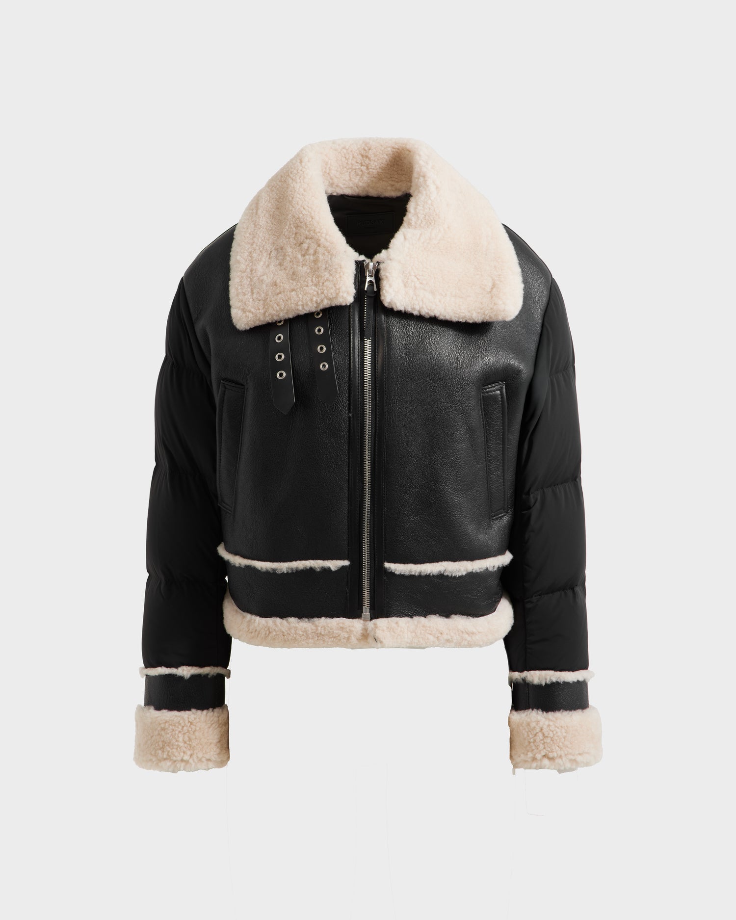 The Rudsak ANA - 8125508 Black womens aviator jacket features a large beige shearling collar, front zipper, welt pockets, and shearling trim on the cuffs and hem, displayed on a plain white background.