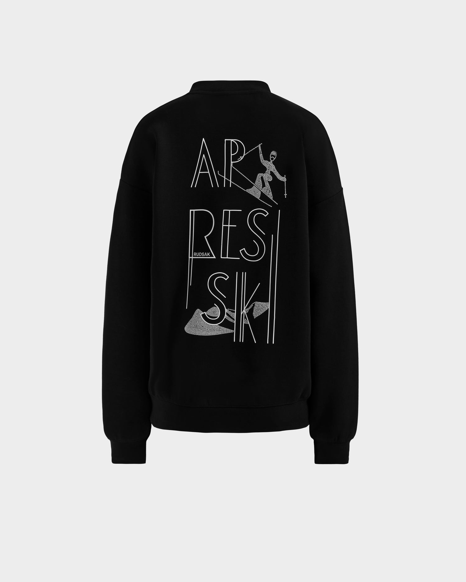 The ARIA - 8525661 Black by Rudsak is a women’s crewneck sweatshirt featuring a bold white APRÈS SKI graphic, skier illustration, and skis on the back—adding style and comfort to your winter wardrobe.