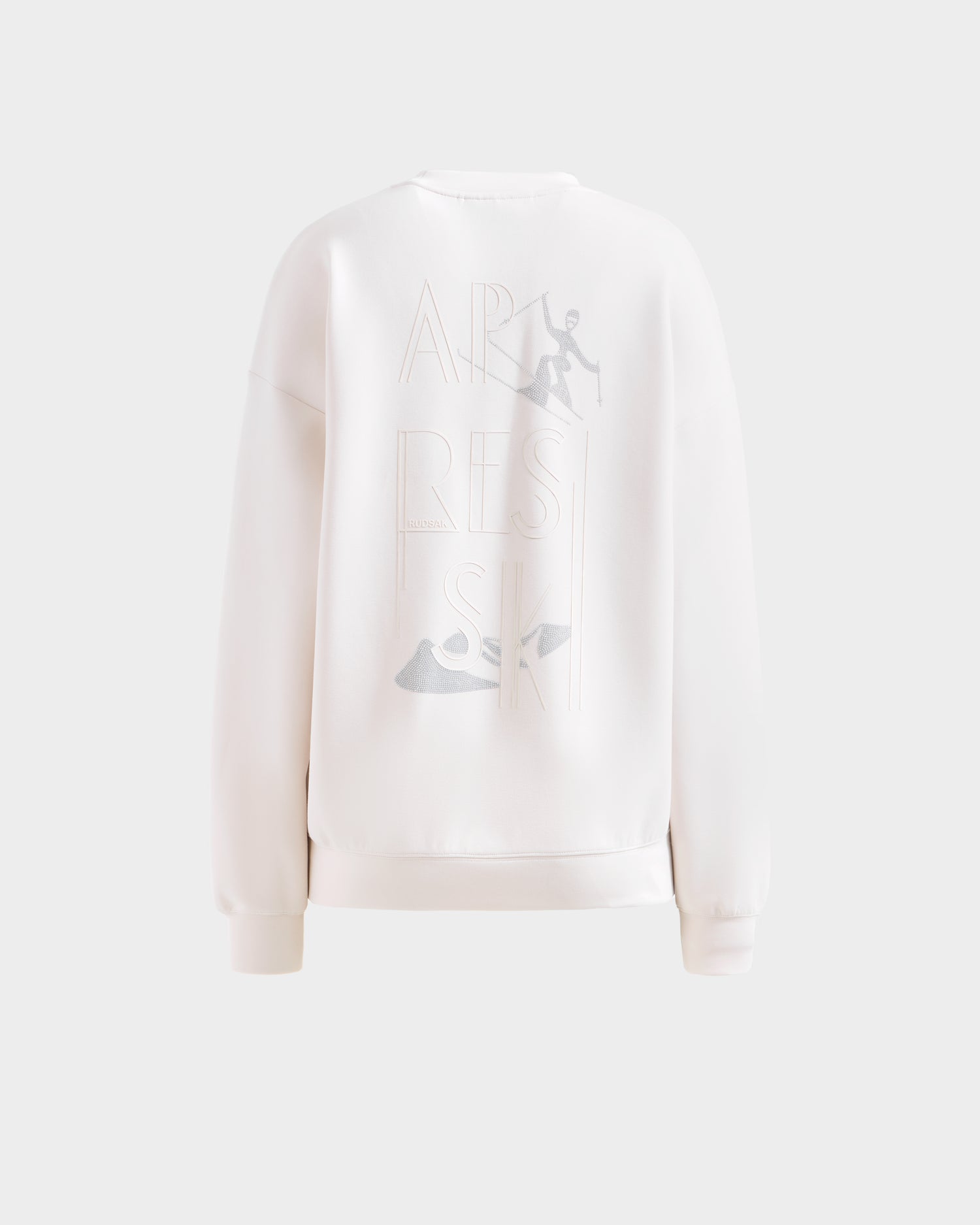 The Rudsak ARIA - 8525661 Vanilla women’s crewneck sweatshirt is shown from the back, featuring subtle embroidered APRES SKI text, a skiing figure, and a ski boot for the perfect après-ski pullover look.