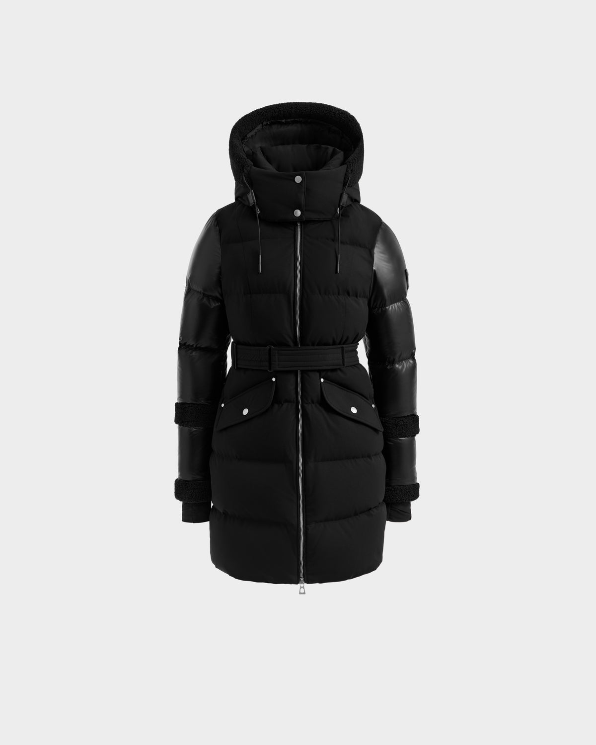 The Rudsak AUDREY L - 8124585 Black/Black is a black, knee-length down puffer jacket with a hood, front zipper, belted waist, and snap-button pockets—crafted from recycled Stormshell fabric and shown on a plain light gray background.