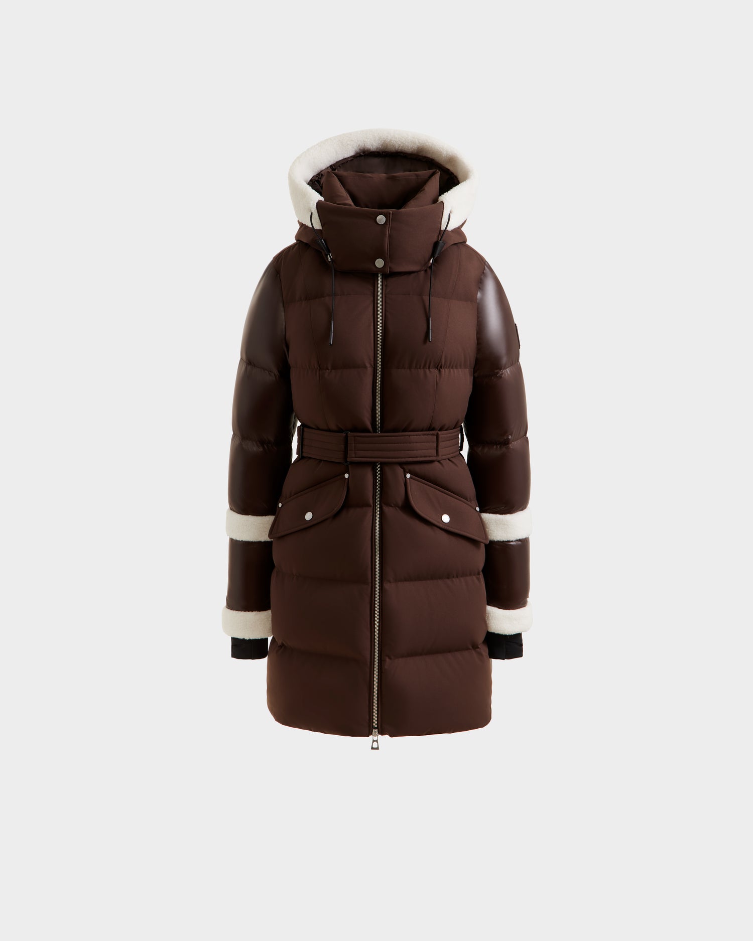 The Rudsak AUDREY L - 8124585 Espresso is a brown, knee-length down puffer jacket with a hood, belted waist, large front pockets, and white shearling trim on the hood, cuffs, and sleeves, shown against a white background.