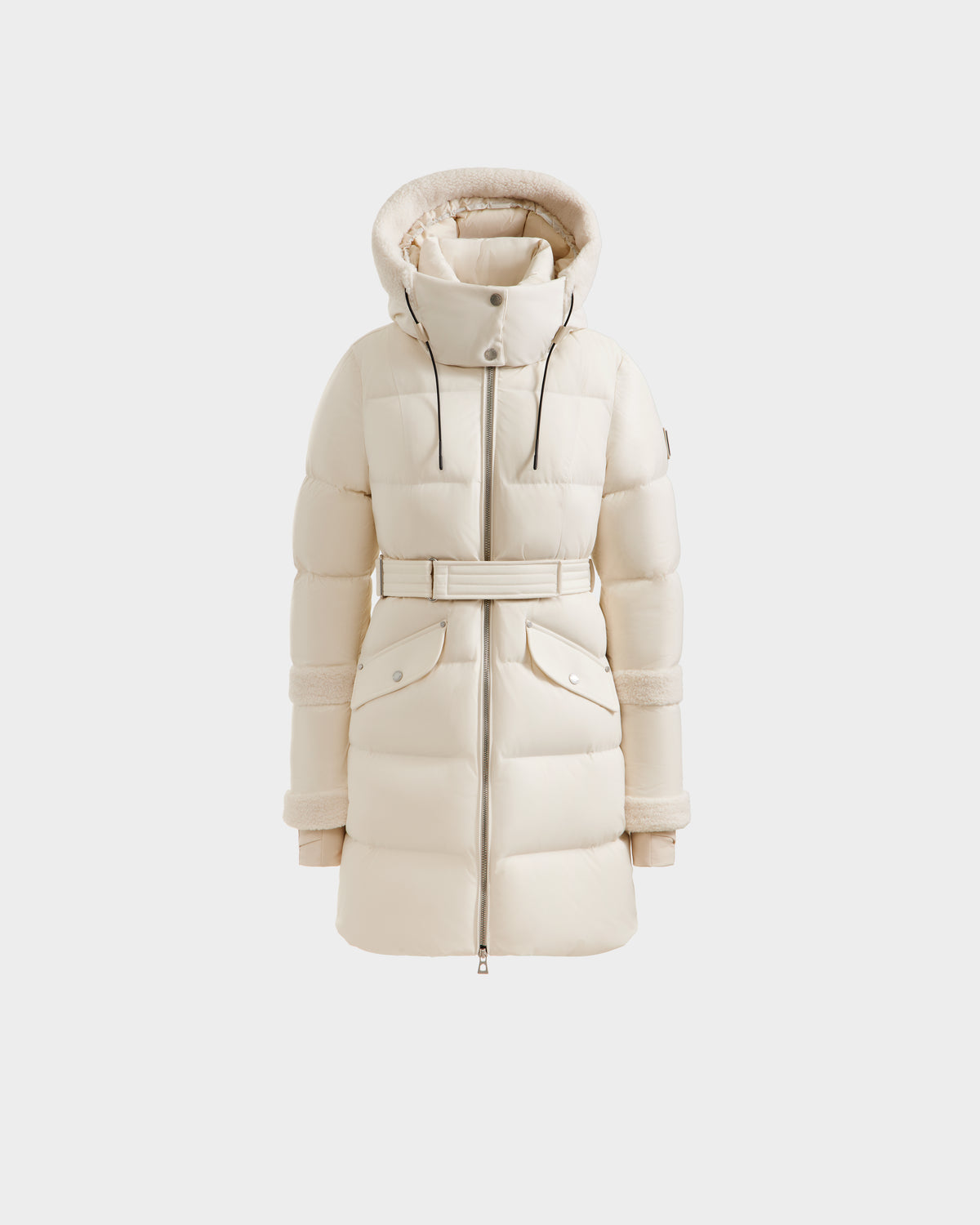 The Rudsak AUDREY L - 8124585 Vanilla is a cream-colored, knee-length down puffer with a hood, high collar, front zipper, belted waist, and large flap pockets. Insulated with RDS certified down for warmth and sustainability.