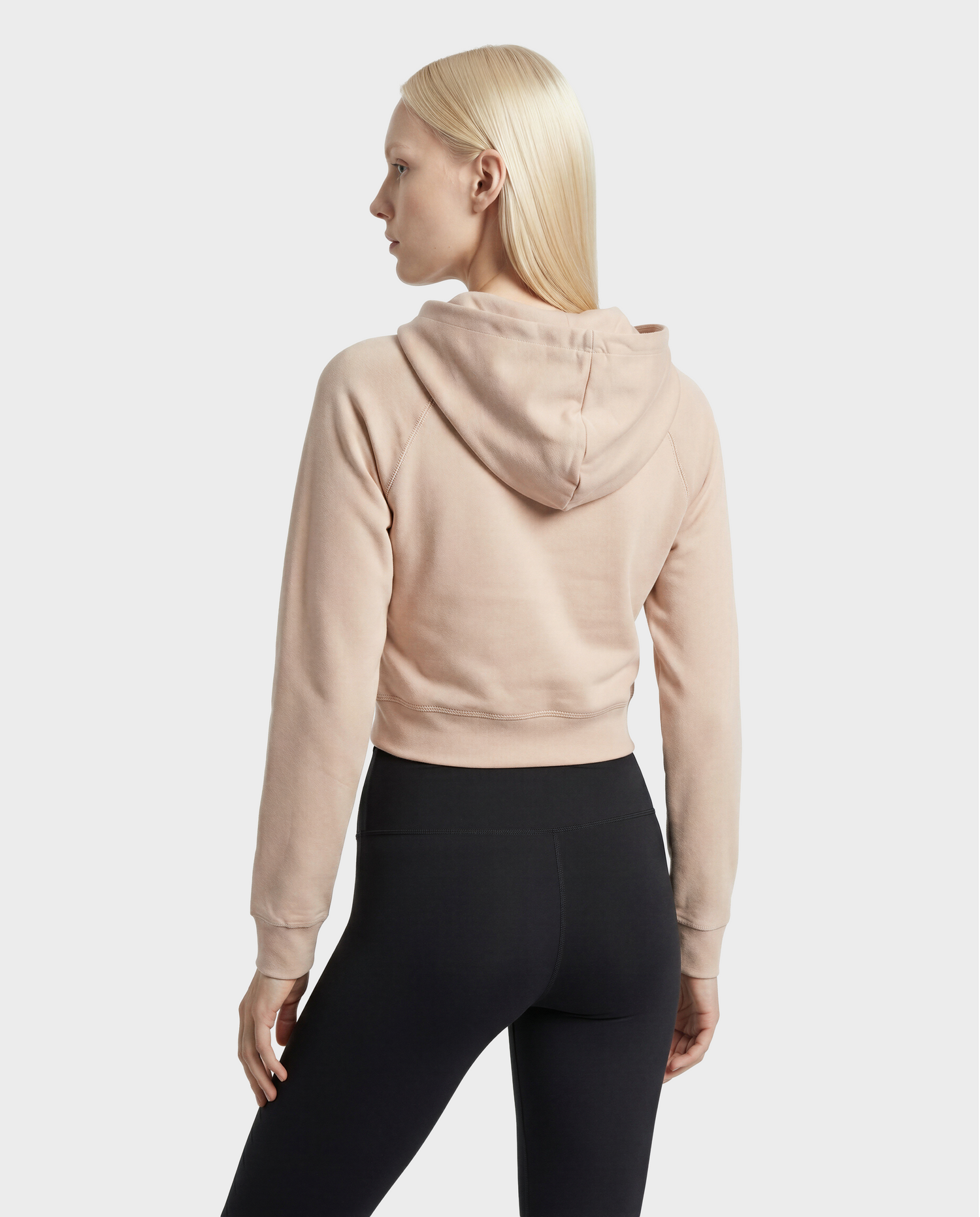 A woman with straight, light blonde hair is standing against a plain background, facing away and looking to the side, wearing the Rudsak SAMMY - L523014T Top in Cream.