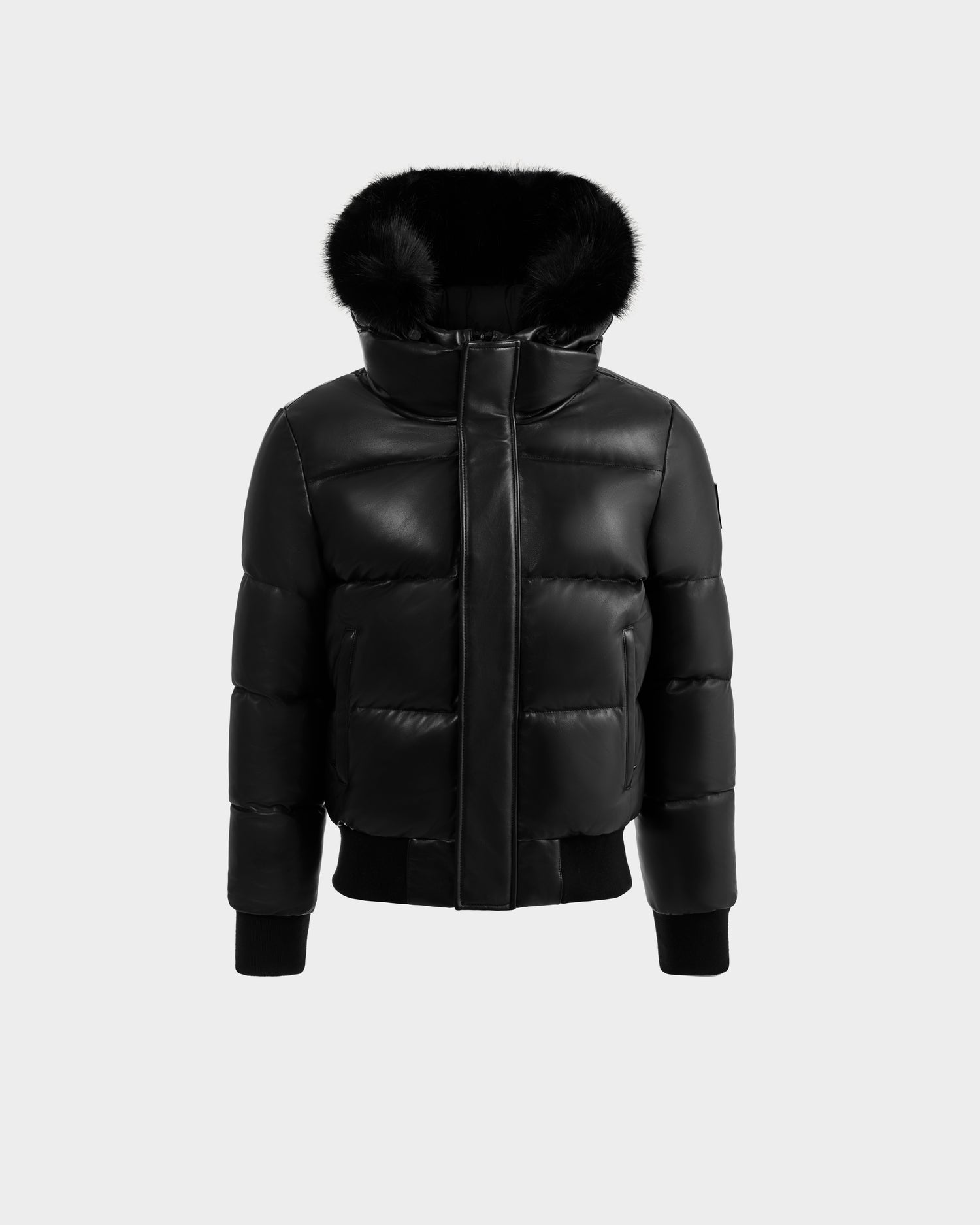 The RUDSAK BOND X - 6122525 BLACK is a black quilted men's jacket with a shiny finish, front zipper, ribbed cuffs and hem, plus a hood lined with black faux fur, shown on a plain light gray background.