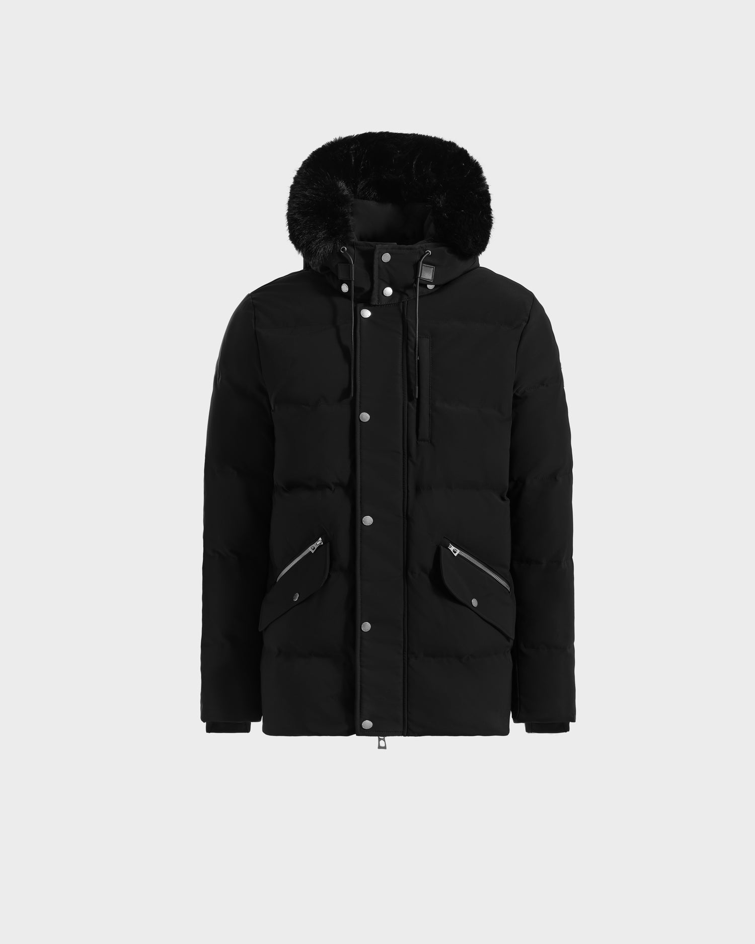 The Rudsak BRADY - M125510 Black is a men’s quilted down parka with a fur-trimmed removable hood, front snap buttons, zippered and flap pockets—an essential winter piece shown on a plain light gray background.
