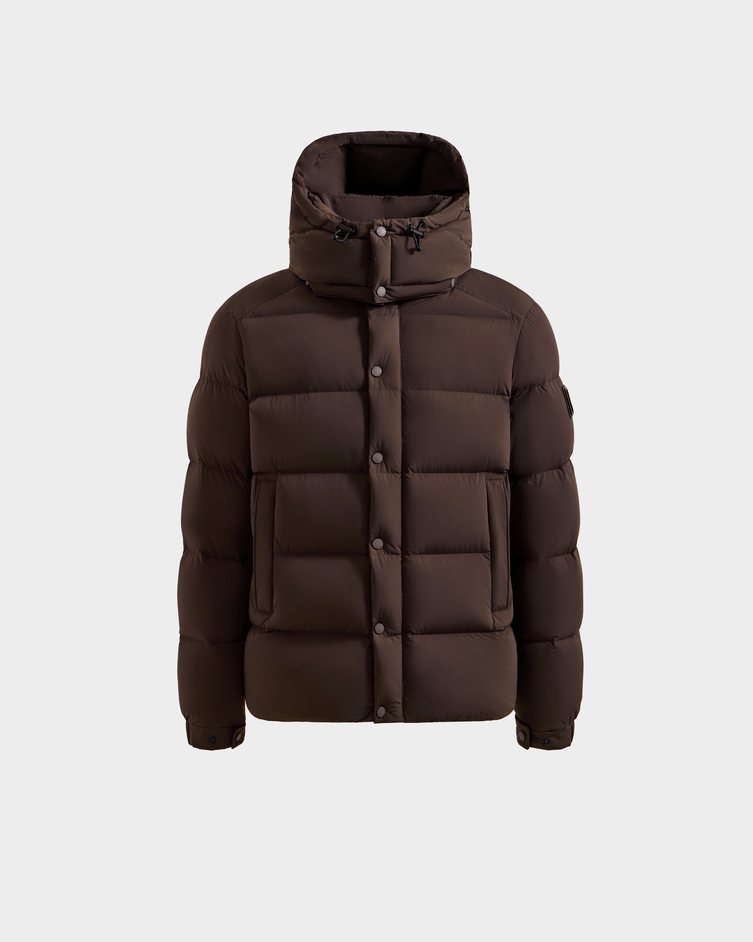 The Rudsak BRAYDEN M-S - M125524 Espresso is a men’s down puffer jacket with a hood, front snap buttons, visible quilted stitching, two front pockets, and a high collar, shown against a plain light background. RDS-certified down.