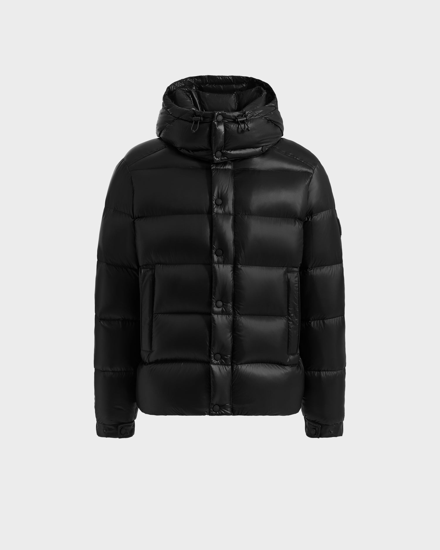 The Rudsak BRAYDEN S - M125525 Black men’s down puffer jacket features water-resistant fabric, a hood, front snap buttons, and two large front pockets, shown against a plain light gray background.