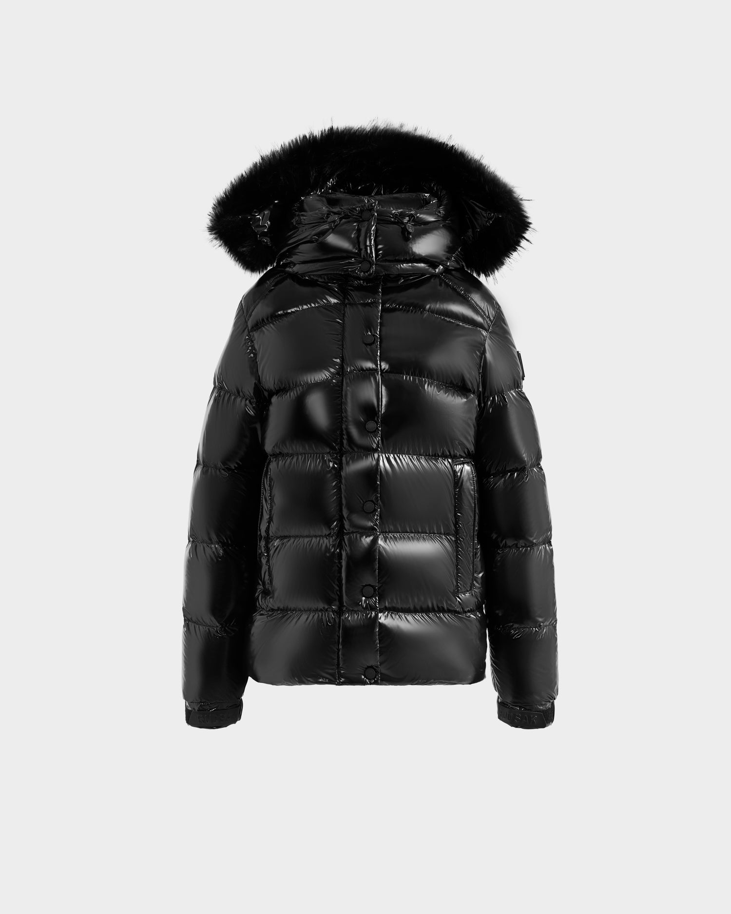 The Rudsak BREE S - L125583 Black is a shiny black women’s down puffer jacket with an ultra-gloss finish, removable faux fur-trimmed hood, long sleeves, and front snap buttons, shown against a plain light gray background.