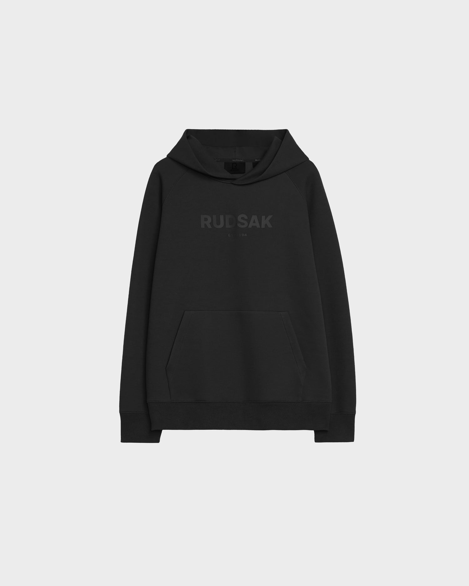 The BRIAR - 9525001 Black W hoodie by Rudsak is a black unisex style made from a premium cotton blend with a front pocket and “RUDSAK” in dark letters across the chest, shown on a light gray background for a casual vibe.