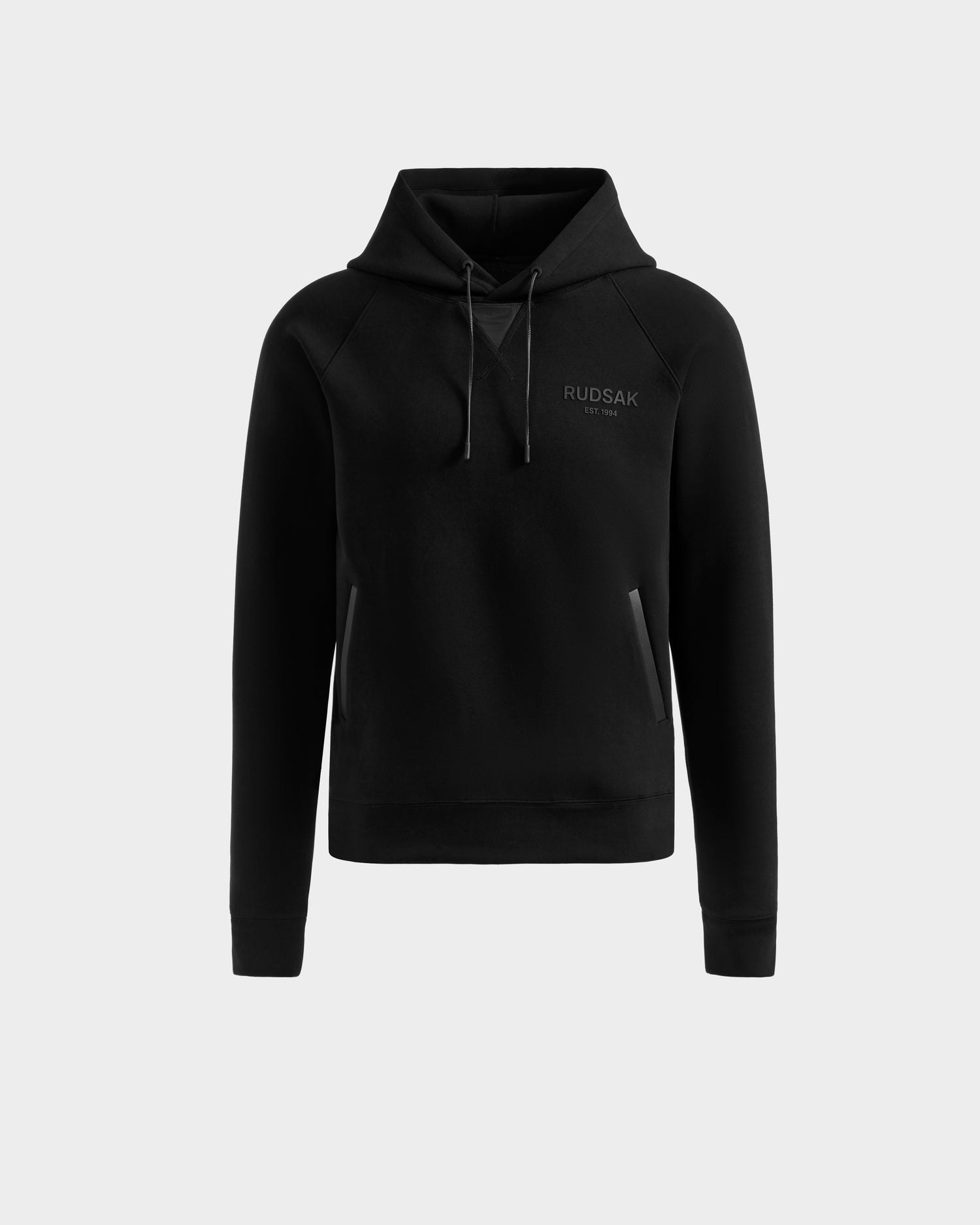 The Rudsak BROOKLYN - 6525593 Black hoodie is a cotton-blend urban sweater featuring a front pocket, drawstring hood, and subtle logo on the left chest, showcased against a plain light gray background.