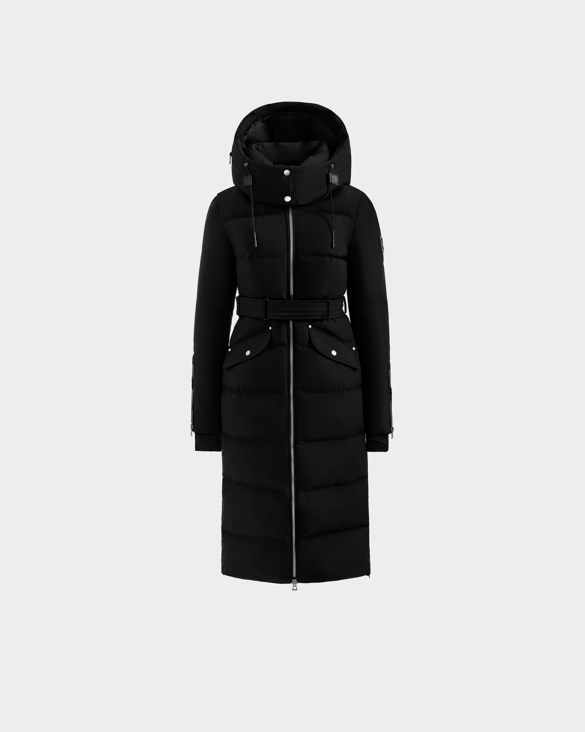 The CALI H - 8125614 Black by Rudsak is a long black women’s down parka with a hood, front zipper, belted waist, and two front flap pockets, made with high-loft down for warmth. Shown on a plain light gray background.