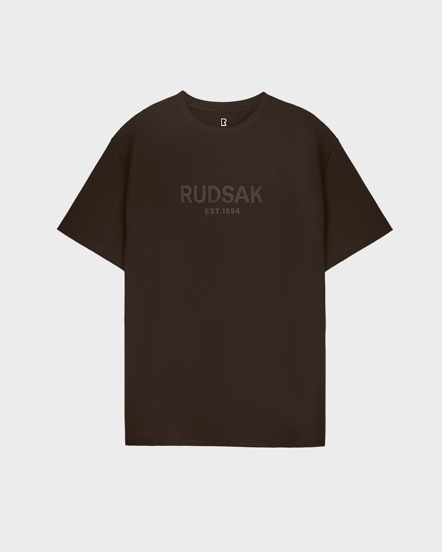 The CASEY - 6525037 Espresso by Rudsak is a classic mens T-shirt featuring subtle RUDSAK EST.1994 lettering across the chest, shown against a light gray background.
