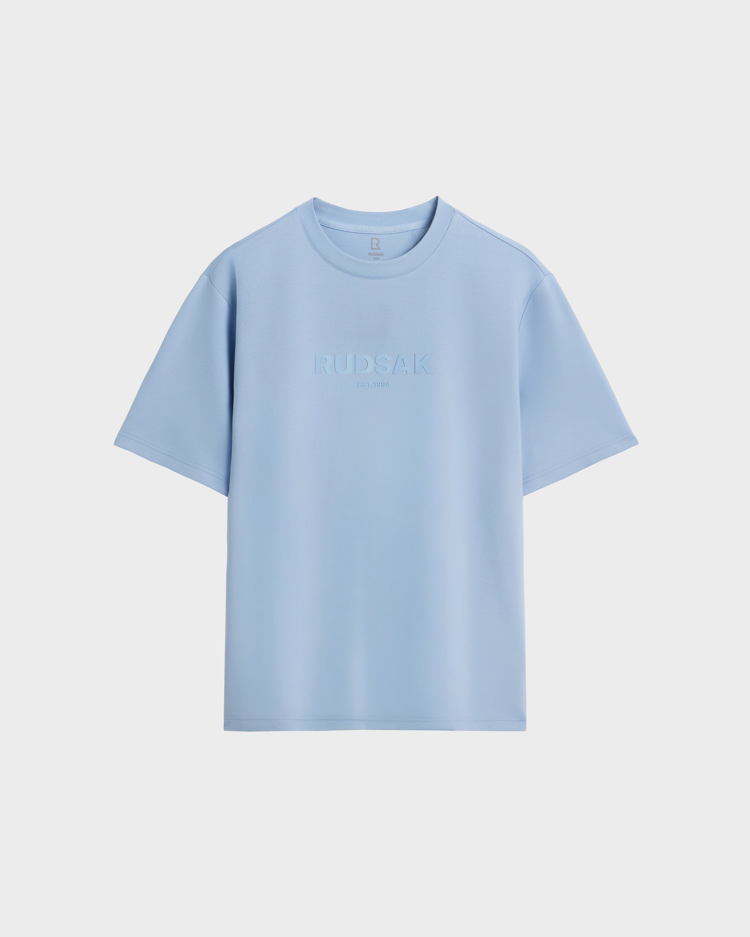 The Rudsak CASEY - 6525037 Sky Blue men’s crew neck T-shirt features an embossed RUDSAK logo on the chest and is showcased against a plain white background—an essential, comfortable style.