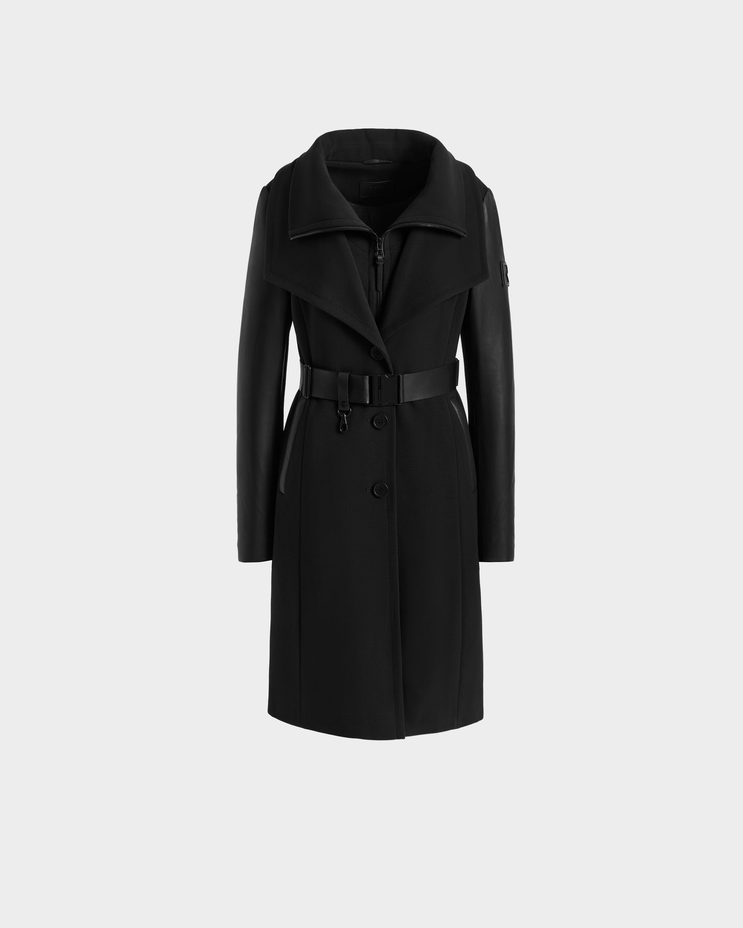 The Rudsak CELESTE - L124542 Black is a modern luxury trench coat with leather sleeves, a wide collar, belted waist, and button closure, shown on a light gray background—an ideal transitional piece for any season.