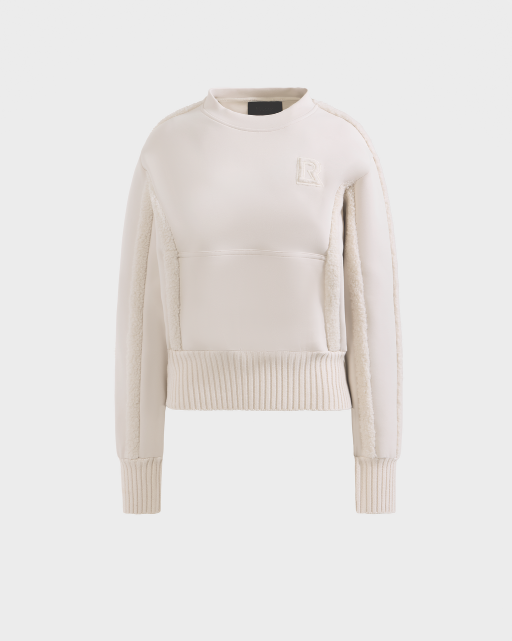 The Rudsak CHANA - 8525656 Vanilla is a cream women's crew neck sweatshirt with ribbed cuffs and hem, textured side panels, and an embroidered R logo on the chest, offering subtle après-ski chic style on a plain white background.