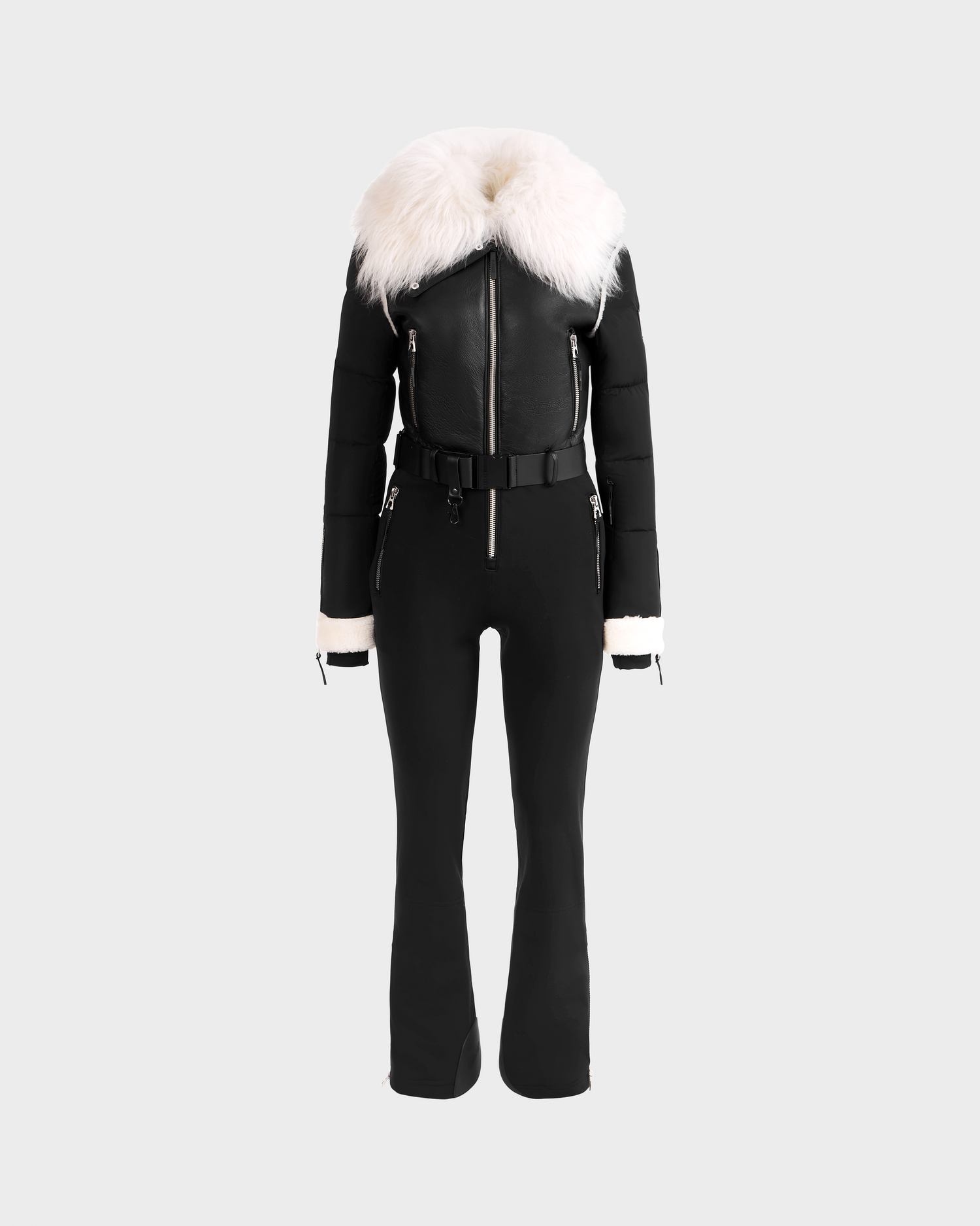 The Rudsak CHYNTIA - 8125611 Black is a black fitted jumpsuit with a wide white faux fur collar, belted waist, zipper details, and white faux fur cuffs. Displayed on a headless mannequin. Pre-order now; ships by November 30th.