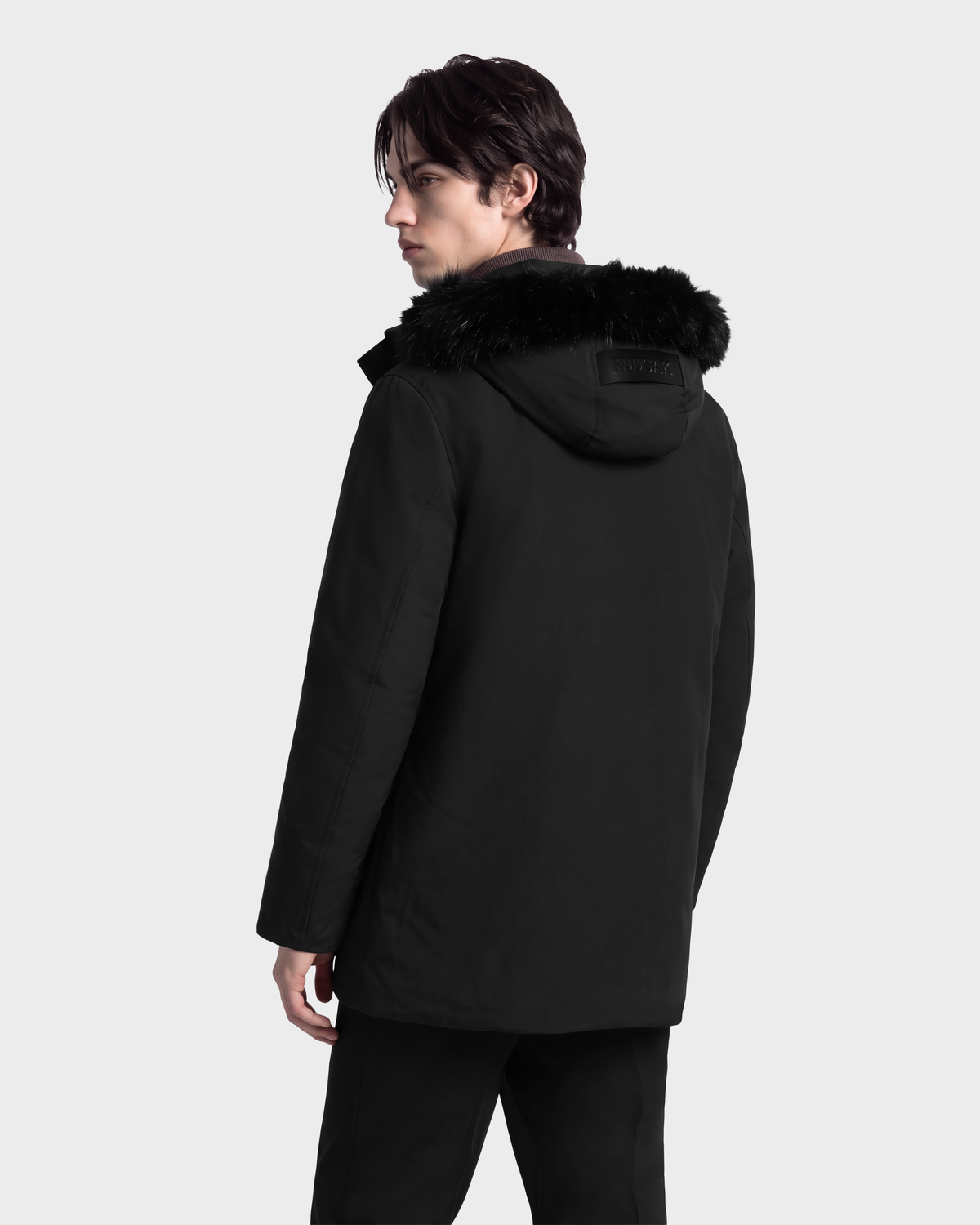 A man wearing an EDWARD - 6126501 Black winter parka with a faux fur-trimmed hood.