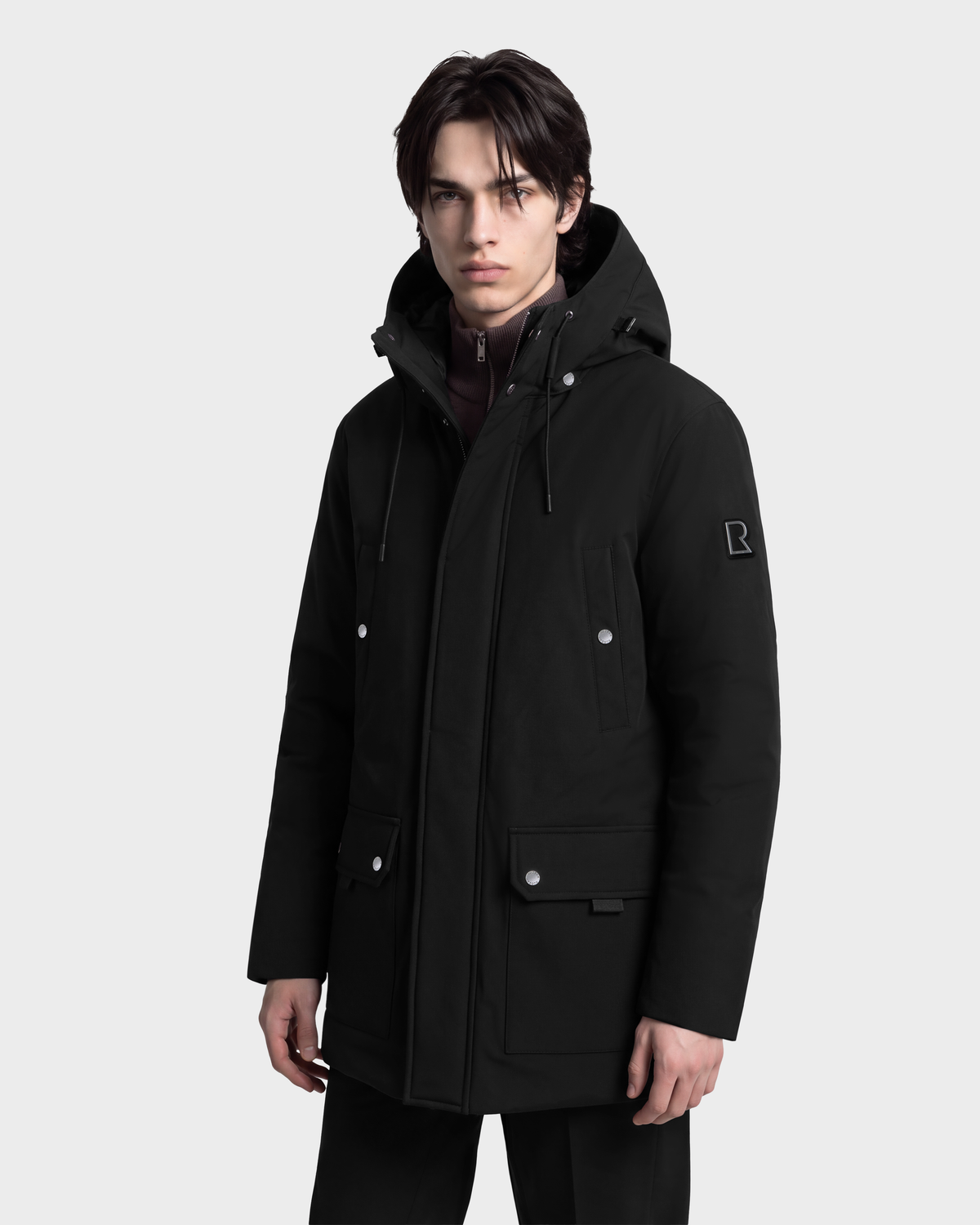 A man wearing a black RUDSAK EDWARD - 6126501 hooded duck down winter parka featuring a front zipper and snap-button flap pockets.