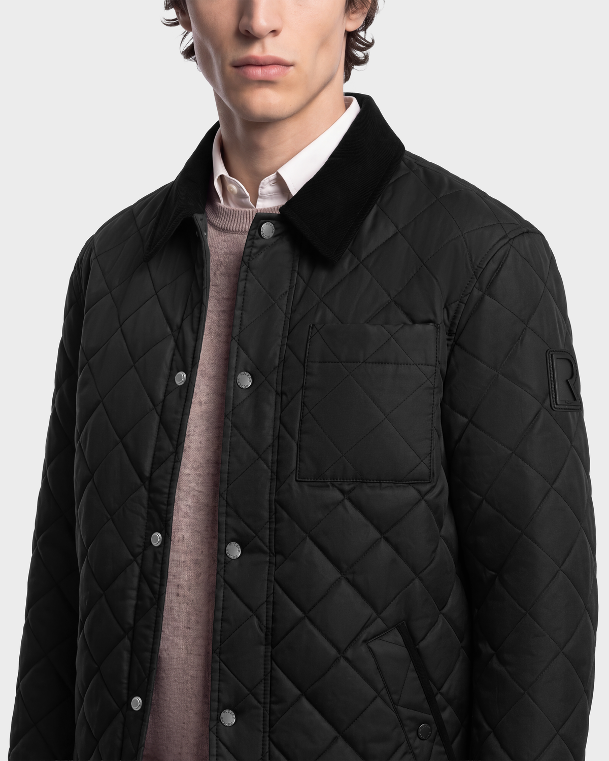 A Rudsak MONTY - 6126722 Black quilted jacket with a dark corduroy collar, a chest pocket, and snap button closures, worn over a light sweater and collared shirt.