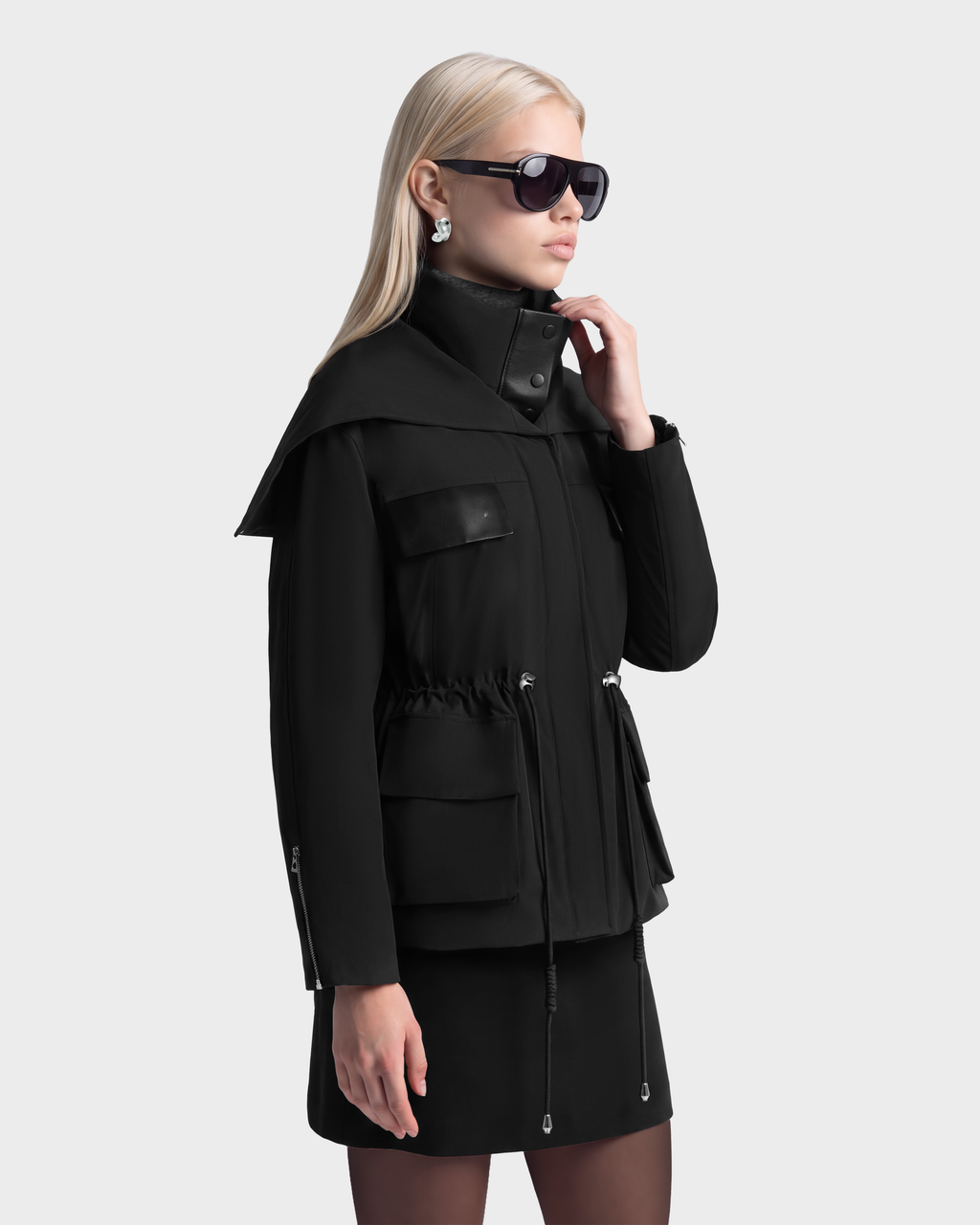 A person wearing a black Rudsak ROSALINDA - 8126523 insulated duck down parka with a high collar, drawstring waist, and large flap pockets.