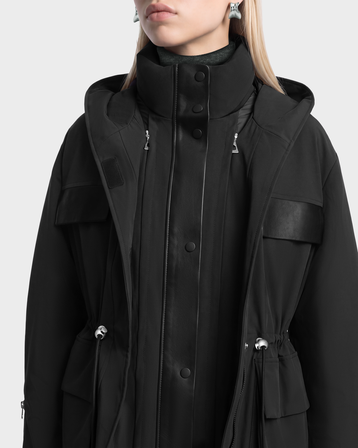 A person wearing a black Rudsak ROSALINDA - 8126523 Black insulated duck down parka with a high collar, snap-button placket, and drawstring waist.