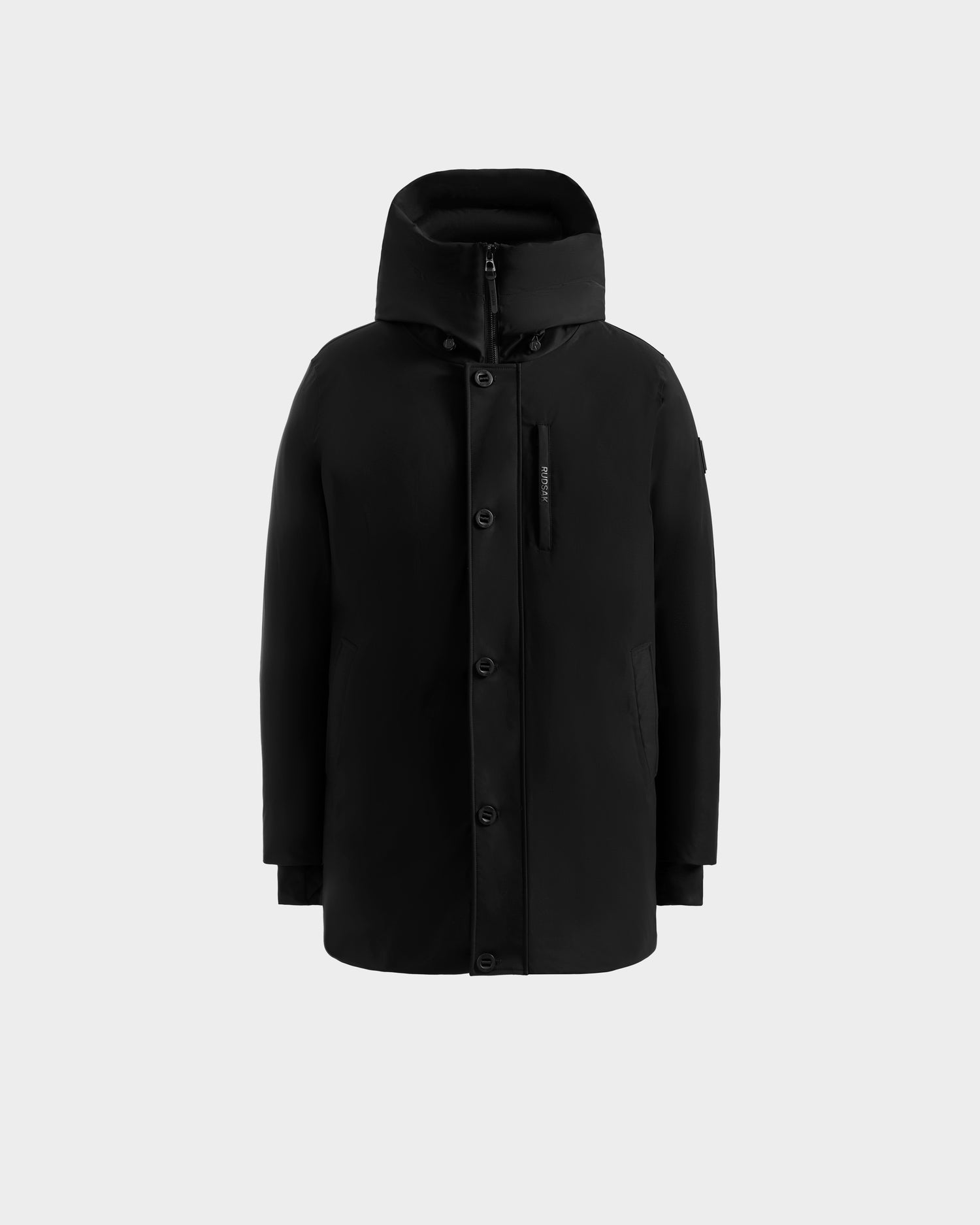 The Rudsak COREY - M125512 Black men’s down parka features a hood, front zipper and button closure, side and chest pockets, and RDS-certified down fill for winter warmth. Displayed on a plain light gray background.