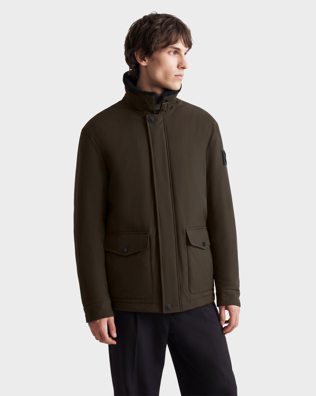 A man wearing the Rudsak ANTOINE - 6126506 Olive utility jacket, featuring a high collar, button closure, and two flap pockets.