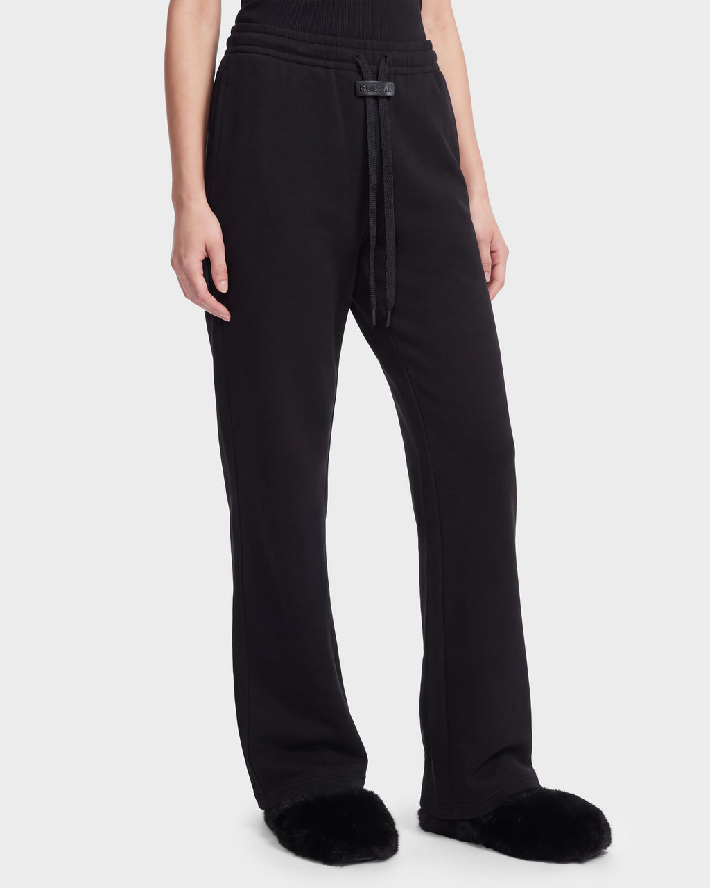 Rudsak ANGEL - 8526725 Black sweatpants featuring a drawstring waist and straight-leg fit, styled with black slippers for a refined off-duty look.