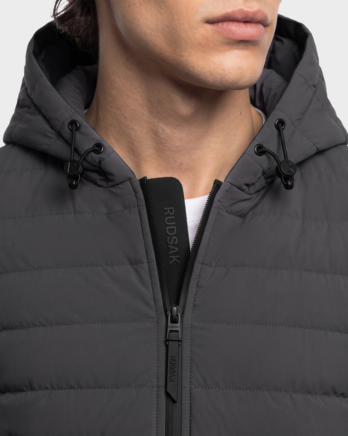 Close-up of a person wearing a DEE MAT - 6124028 Grey charcoal grey quilted jacket with a hooded collar, featuring a zippered front and a branded trim along the inner placket.