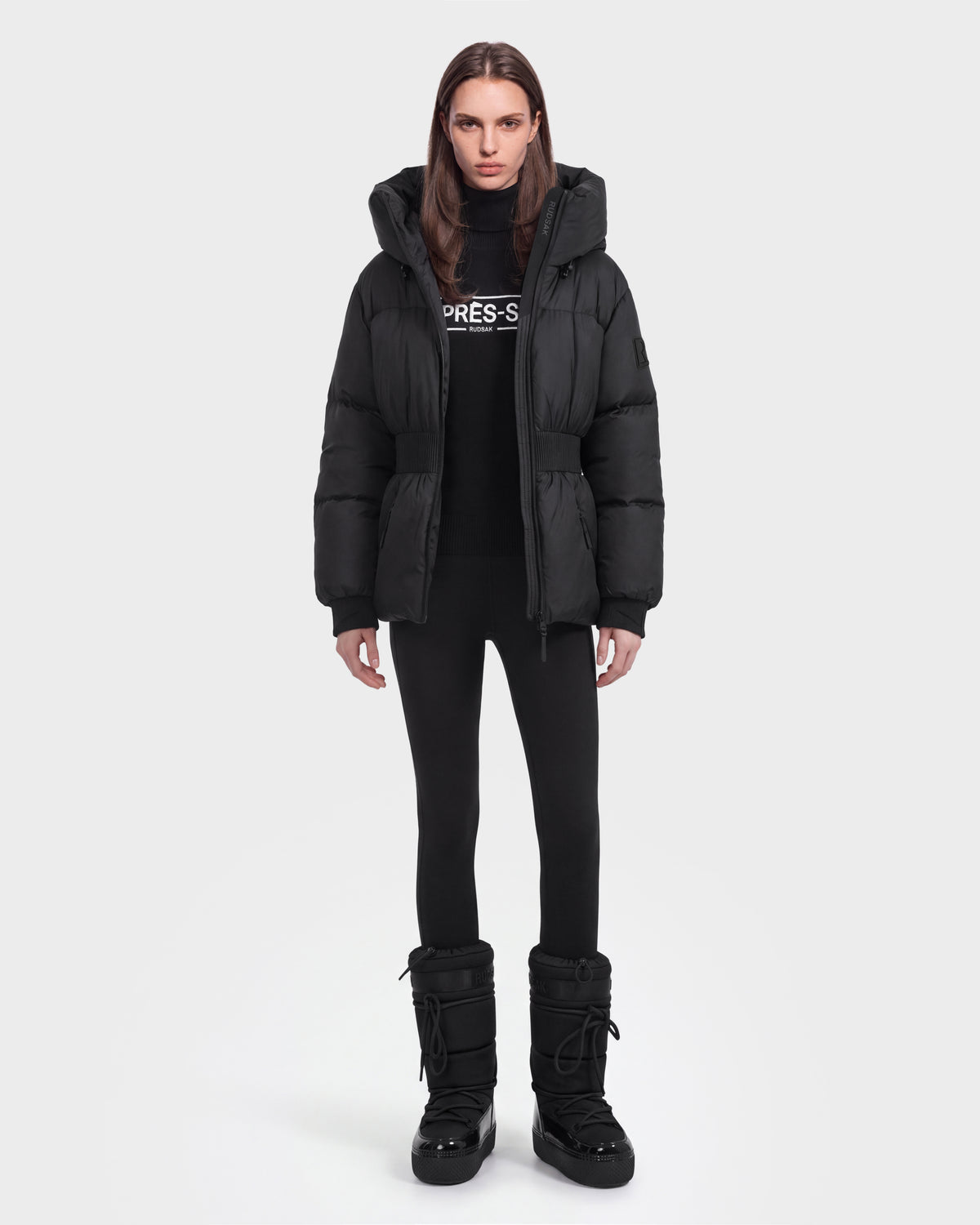 A person wearing the Rudsak DIAMOND - 8126772 Black jacket, black leggings, and black winter boots stands facing forward against a plain white background.