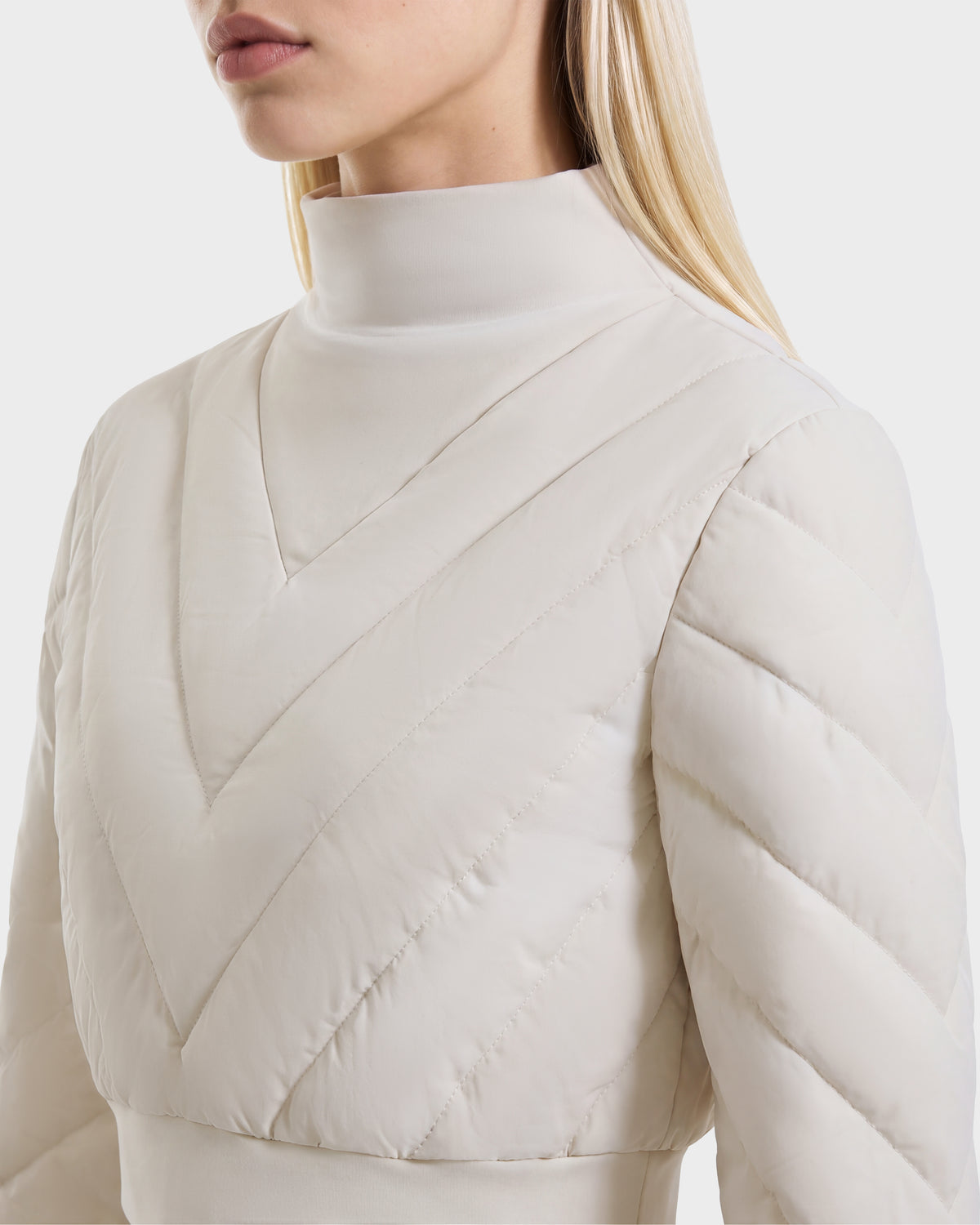 Cream-colored RUDSAK KATYA - 8526531 Vanilla mock-neck quilted jacket with a V-shaped stitch pattern, serving as a versatile après-ski layer.