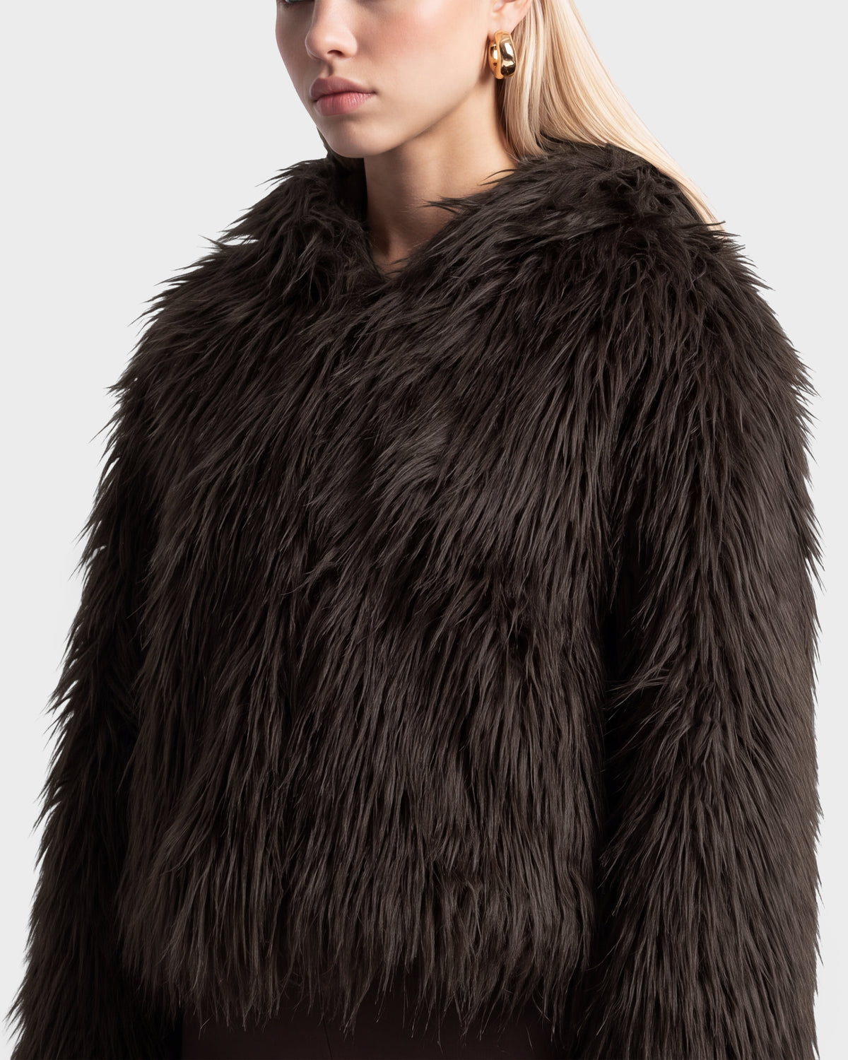 A person wearing an ELLISON - 8525678 Espresso oversized faux fur hoodie in a dark brown, shaggy texture.