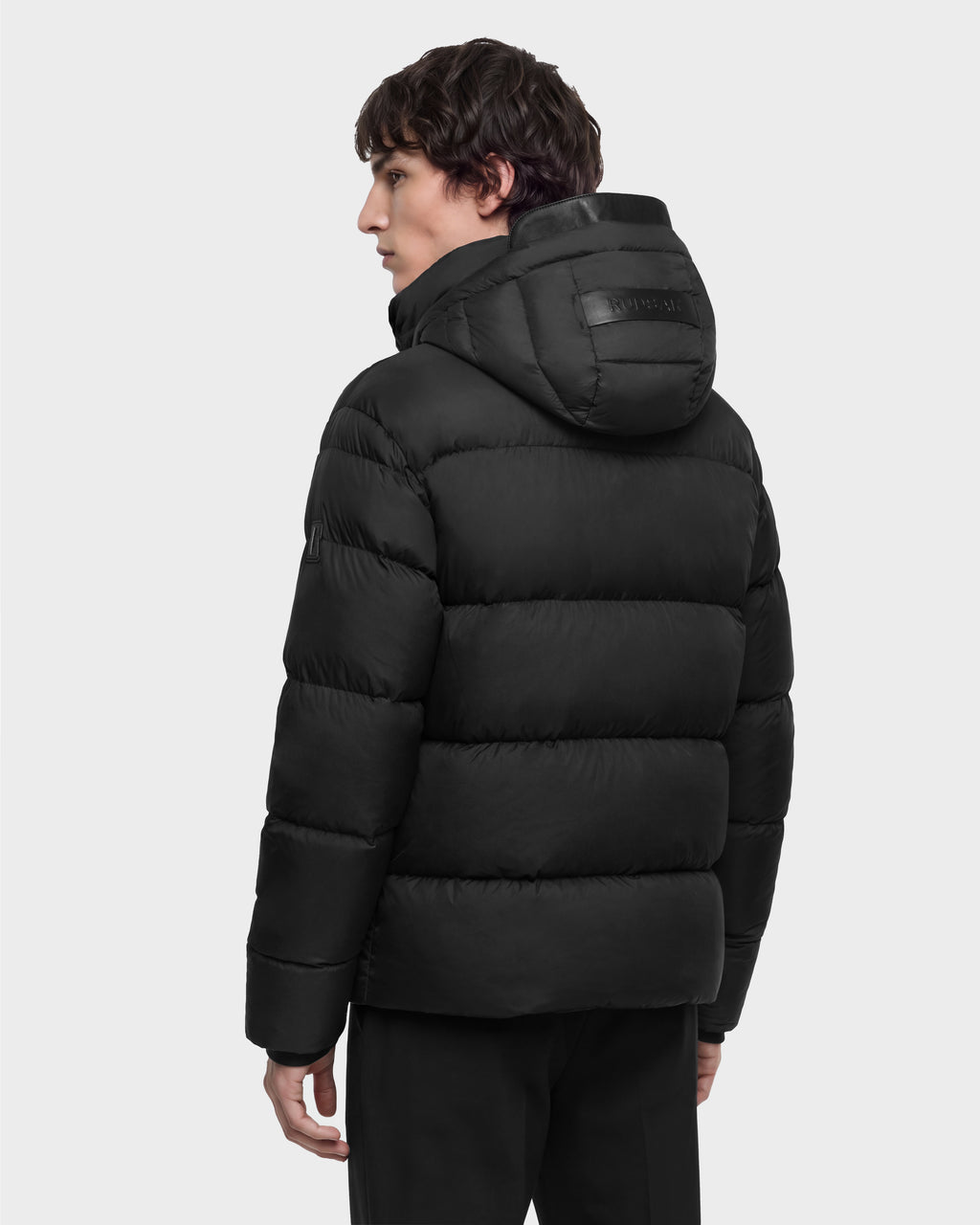 A person viewed from the back, wearing a black JASON - 6126803 Rudsak high-performance warmth winter puffer jacket with a hood.
