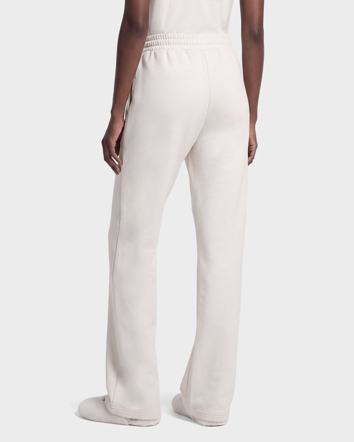 Back view of a person wearing vanilla-colored ANGEL - 8526725 stretch cotton sweatpants with an elastic waistband and matching slippers for a refined off-duty look.