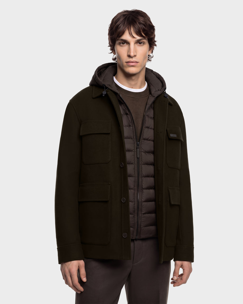 A man wears a dark brown BRUNO - 6126716 Espresso hooded jacket layered over a zip-up puffer vest.