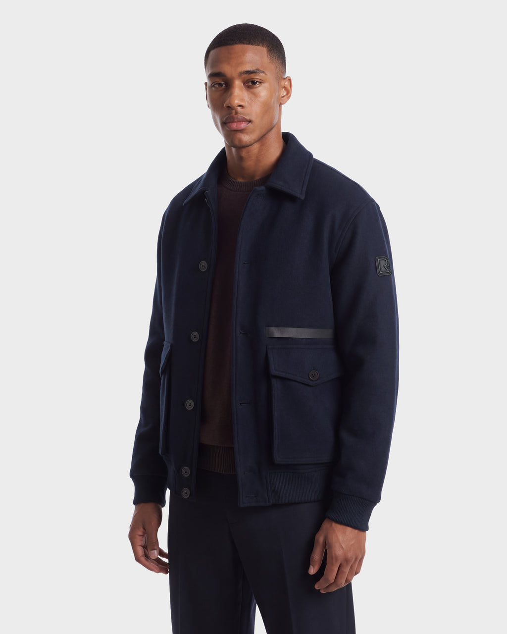 A man wearing the JULIUS - 6126723 Navy wool jacket, featuring a navy blue button-up design with two front pockets and a subtle horizontal stripe detail.