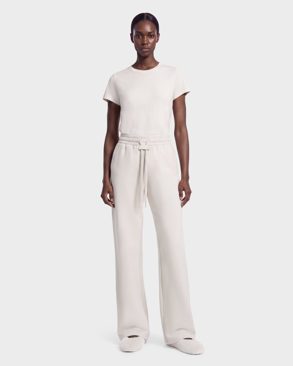A person wearing the ANGEL - 8526725 Vanilla vanilla-colored short-sleeved t-shirt and matching wide-leg drawstring sweatpants, styled for a refined off-duty look.