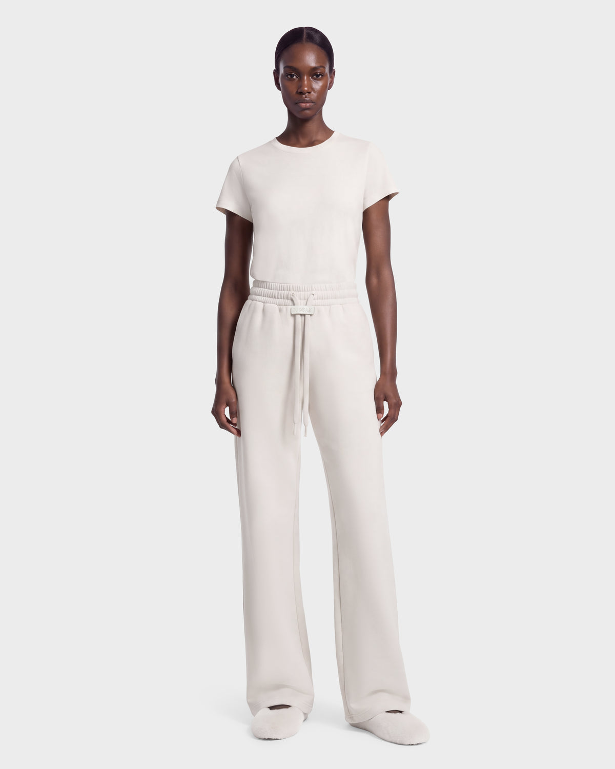 A person wearing the ANGEL - 8526725 Vanilla vanilla-colored short-sleeved t-shirt and matching wide-leg drawstring sweatpants, styled for a refined off-duty look.