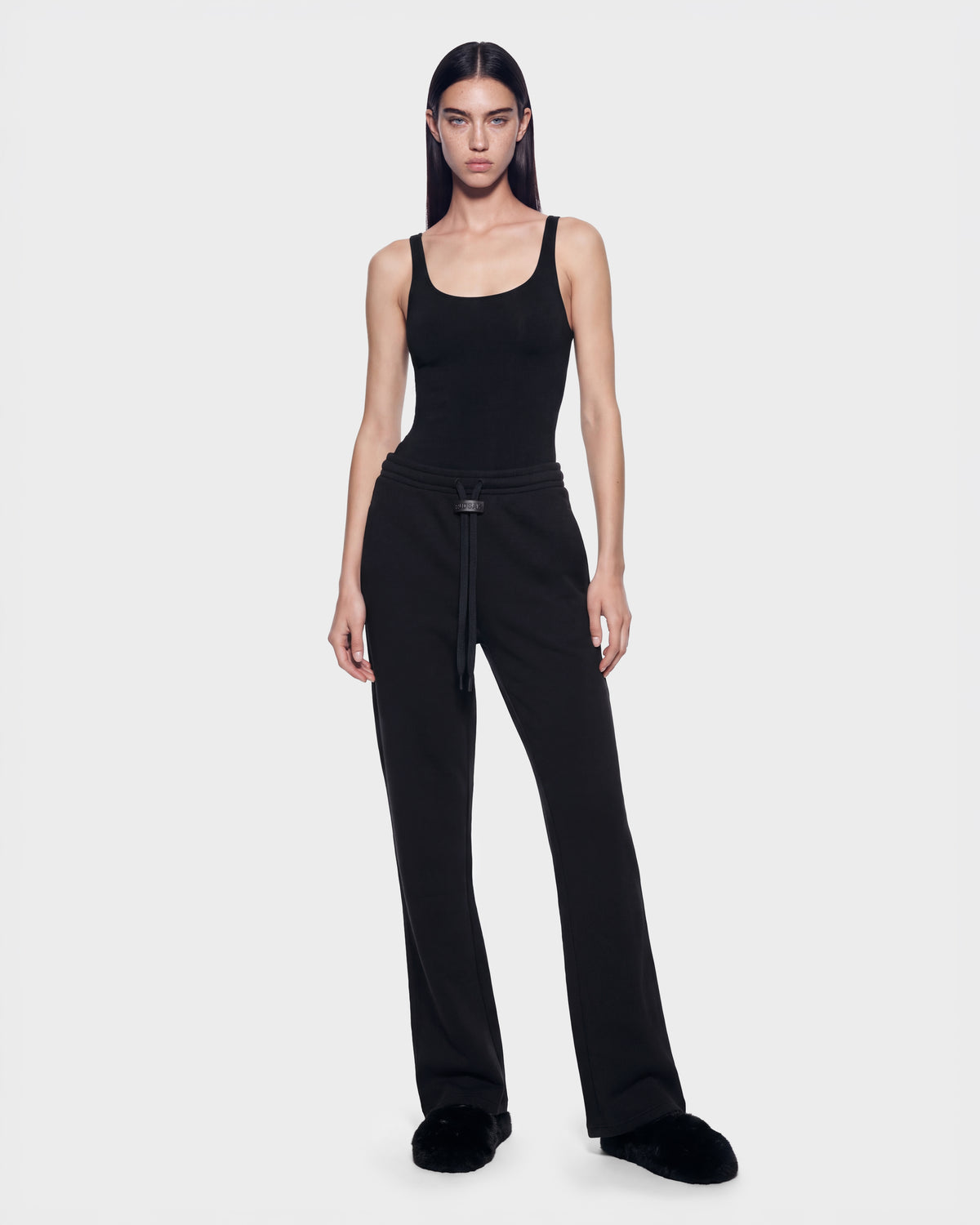A woman wearing ANGEL - 8526725 Black in a black tank top, contemporary sweatpants with a drawstring waist, and black slide sandals for a refined off-duty look.
