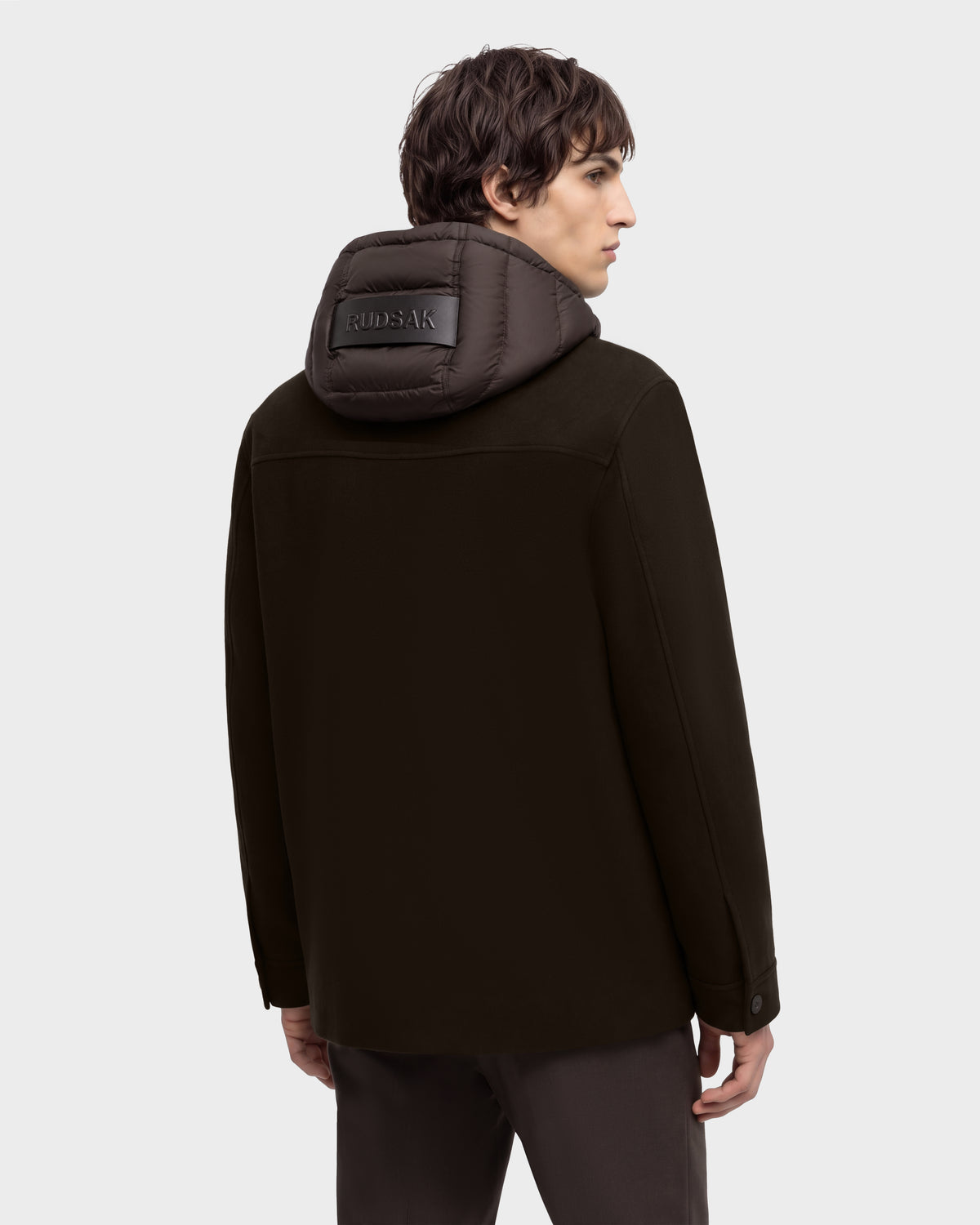 Back view of a person wearing a dark brown BRUNO - 6126716 Espresso jacket with a quilted hooded collar featuring a branded patch.