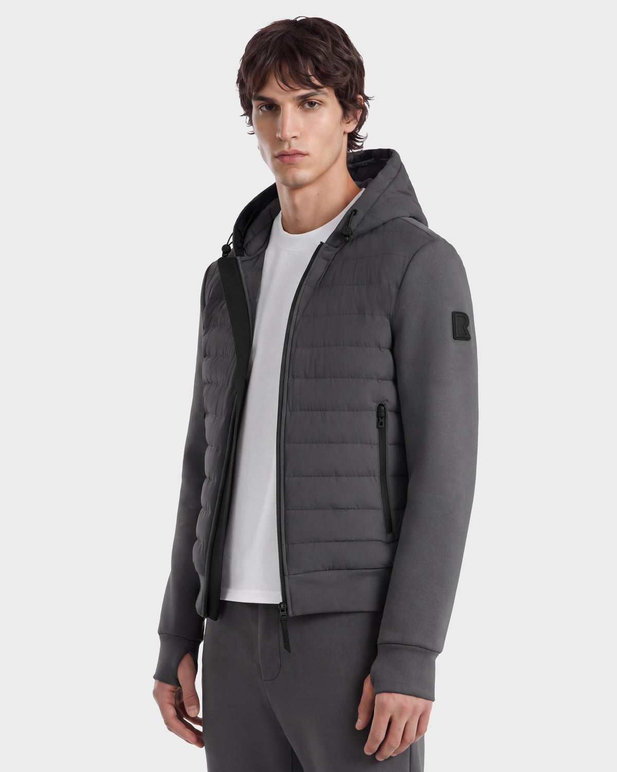A man wears a grey DEE MAT - 6124028 Rudsak urban jacket featuring a quilted front panel and zippered side pockets over a white t-shirt.