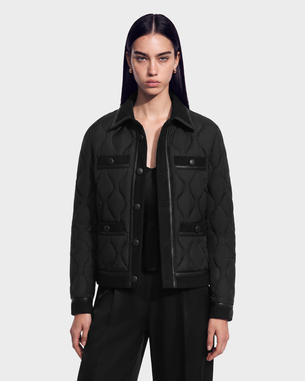 A woman wearing a black JOLIE - 8125036 RUDSAK quilted light down jacket with a collar and button-front closure.