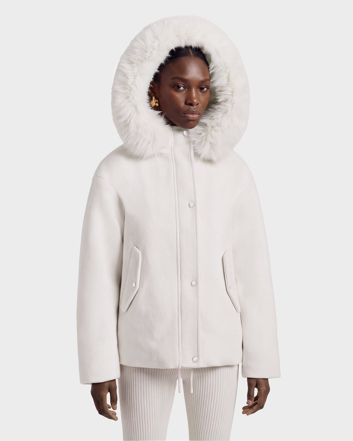 A person wearing a cream-colored Rudsak HAZEL - 8126981 Vanilla wool-blend winter coat with a large, faux-fur trim hood pulled up over their head.