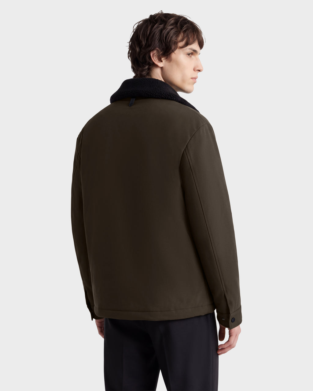 A man seen from behind wearing the Rudsak ANTOINE - 6126506 Olive utility jacket, featuring an olive green color and a dark faux-fur collar.